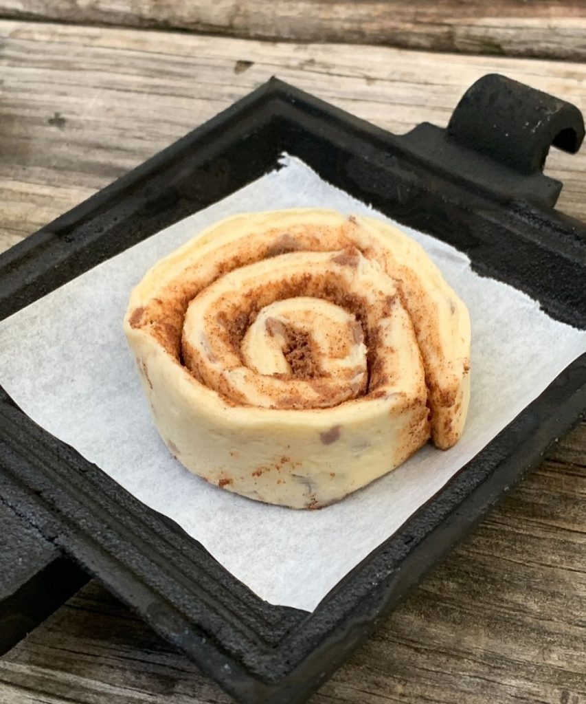 unbaked cinnamon roll on a pie iron